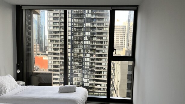 A hotel room with two beds, a large window, and a view of high-rise buildings. - Incredible 2 BR City Apartment (Melbourne)