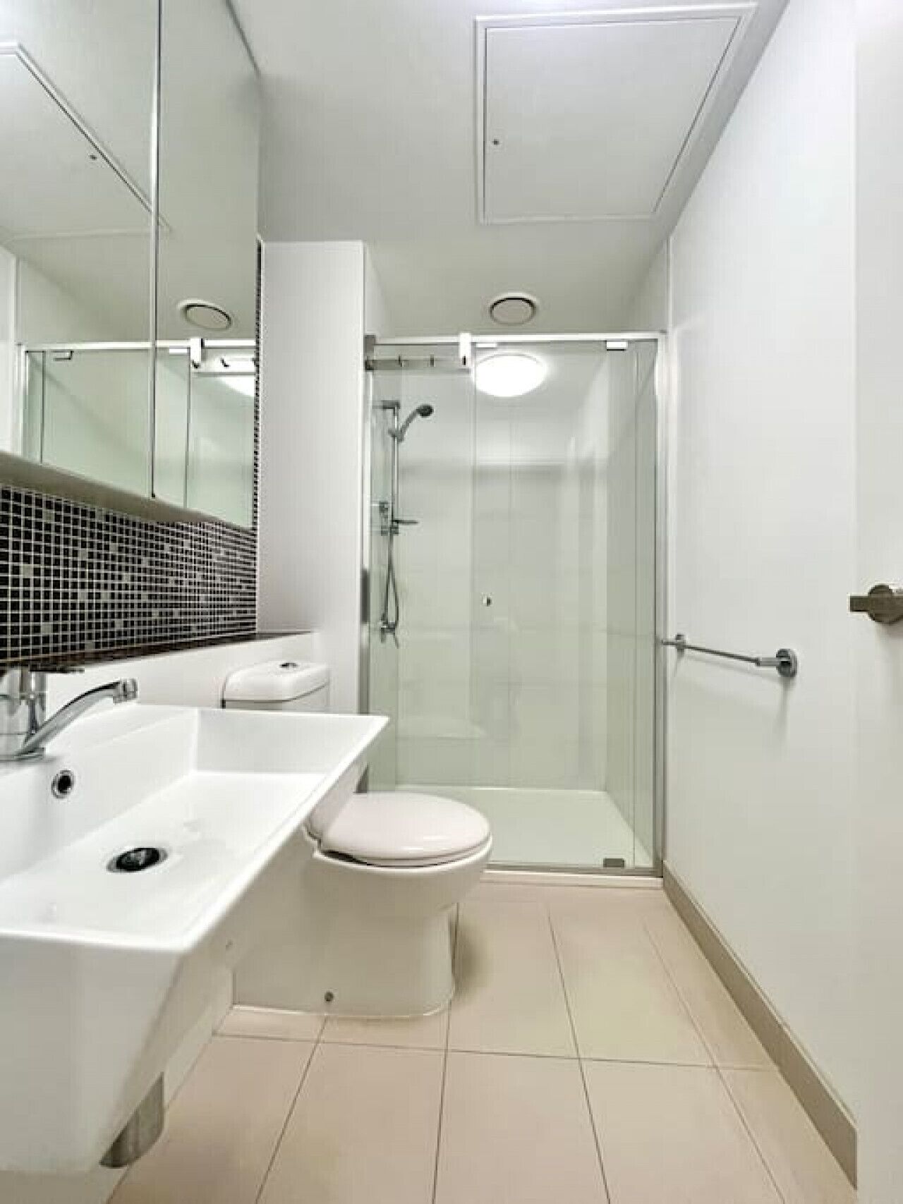 A modern bathroom with a glass-enclosed shower, a white sink, and a toilet.