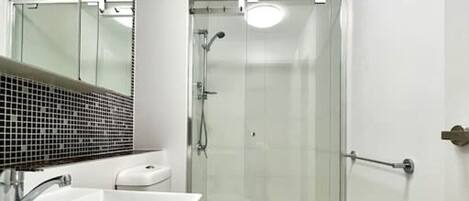 A modern bathroom with a glass-enclosed shower, a white sink, and a toilet.