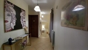 A hallway with a painting of a woman's face on the left, a radiator on the right, and a door at the end.