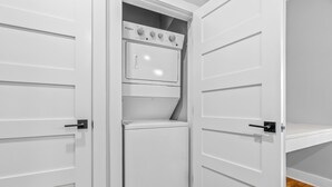 Una lavandería con lavadora y secadora Whirlpool, puertas blancas y suelo de madera.