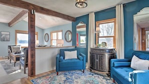 A living room with a blue sofa, a patterned rug, and a wooden beam ceiling.
