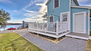A two-story house with a covered porch, a front door, and a small deck.