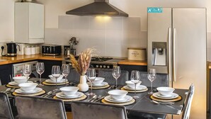 Uma cozinha moderna com uma mesa de jantar posta para seis pessoas, equipada com fogão, micro-ondas e geladeira.