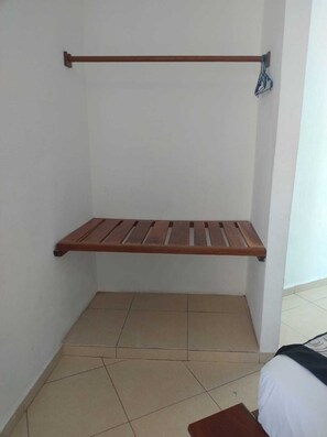 Habitación de esquina con un banco de madera y una barra metálica para colgar objetos.