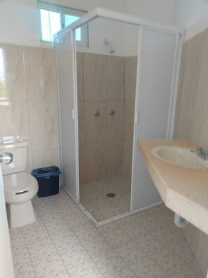 A bathroom with a toilet, a shower enclosure, and a sink. - Hotel Las Palmas en Laurel (Cancun)