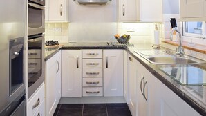 A modern kitchen with white cabinets, stainless steel appliances, and a black tiled floor. - 2 bedroom accommodation in Thirkleby, near Thirsk (Thirkleby, near Thirsk)