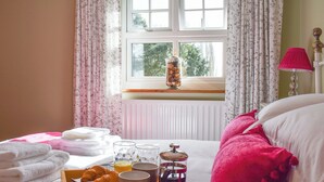 A neatly made bed with a tray of breakfast items, including croissants, coffee, and juice, and a vase with pinecones on the windowsill. - 2 bedroom accommodation in Thirkleby, near Thirsk (Thirkleby, near Thirsk)