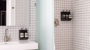 Un baño moderno con lavamanos blanco, espejo y zona de ducha.