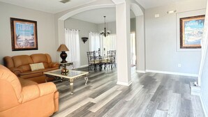 A spacious living area with a sofa, coffee table, and dining table. - High Grove Hideaway, Spacious 5BR Villa w/ Pool Near Disney (Four Corners)