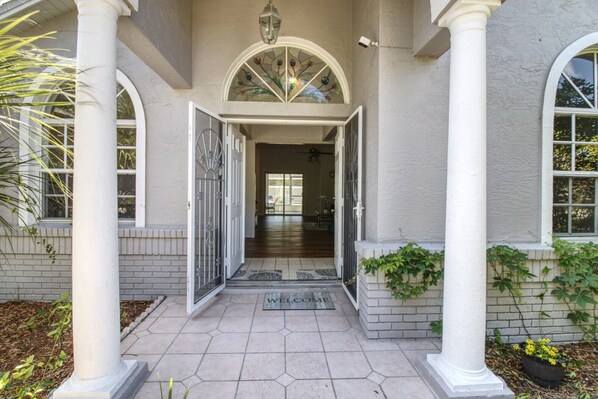 Une entrée de maison avec un paillasson, une porte et un escalier menant à l’intérieur.