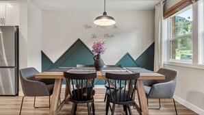 Una cocina moderna con una mesa de madera, cuatro sillas y una lámpara colgante.