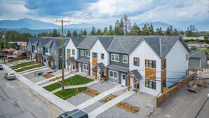 Una hilera de casas urbanas modernas con un diseño uniforme, que presenta una combinación de exteriores grises y blancos, y un jardín delantero bien cuidado.