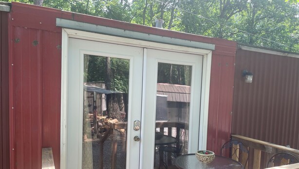 A deck with a glass door leading to an outdoor area with a table and chairs.