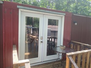A deck with a glass door leading to an outdoor area with a table and chairs. - Remodeled Studio house on a farm (McMinnville)