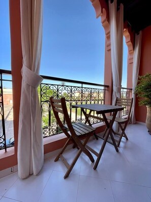 Ein Balkon mit Tisch und Stühlen, einem Geländer und Blick zum Himmel.