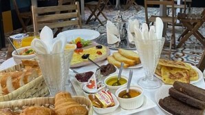 A dining area with tables set for breakfast, including pastries, bread, and various spreads.
