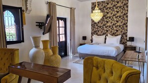 A hotel room with a bed, two chairs, a small table, and decorative vases.