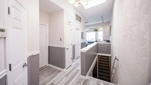 Ein modernes Interieur mit einer Treppe, weißen Wänden und einem sichtbaren Küchenbereich im Hintergrund.