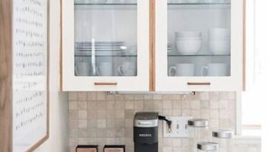 Eine Küche mit zwei Schränken, einer Kaffeemaschine und einer Aufbewahrungsbox für Tee und Kaffee.