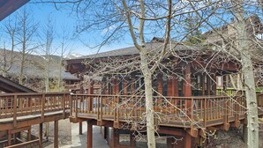 A wooden building with a balcony and a tree in front.