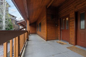 A wooden cabin with a covered porch, a concrete floor, and a wooden door with a window. - Tyra Penthouse Ski-In/Out — 4BR, Sleeps 12 (Breckenridge)
