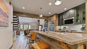 A modern kitchen with a large island, bar stools, and built-in appliances.