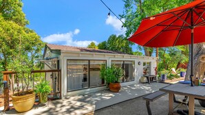 Ein modernes Haus mit Terrasse, großen Fenstern und einem roten Sonnenschirm.