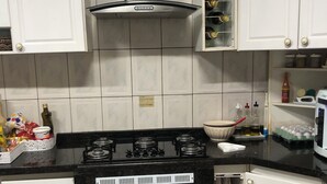A kitchen with white cabinets, a stove, and a microwave. - Single Room Centro Avaré  (Braz II Avaré)