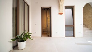 A spacious interior with a potted plant, a glass door leading to a room, and a staircase. - Deluxe apartment (Sanlúcar de Barrameda)