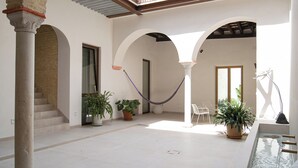 A spacious courtyard with a pool, potted plants, and a hammock. - Deluxe apartment (Sanlúcar de Barrameda)