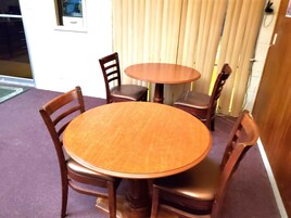 Una mesa redonda de madera con cuatro sillas, una ventana y una puerta con cortina.