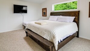 A bedroom with a bed, a ceiling fan, a window, and a flat-screen TV mounted on the wall. - Seiku Vacation Rental w/ Deck & Ocean Views (Seiku)