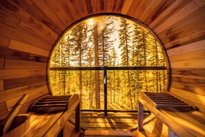 A circular wooden room with a large window, wooden benches, and a staircase leading to the window. - Modern Rustic A-Frame Cabin with Barrel Sauna (Nordegg)
