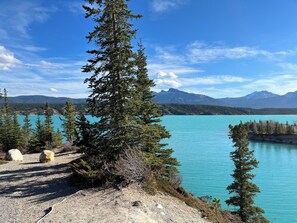 Une vue dégagée sur un lac de montagne, entouré d’arbres, avec une chaîne de montagnes qui se profile à l’horizon.