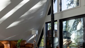 Un salon moderne doté d’un plafond en pente, d’une cheminée, d’un canapé en cuir, d’une table basse en bois et d’un tapis en peau de vache.