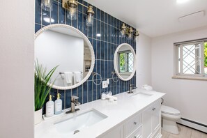 Ein modernes Badezimmer mit zwei Waschbecken, einem großen Spiegel und einer Toilette.