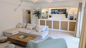 Una sala moderna con un sofá seccional, una mesa de centro de madera y una alfombra estampada.