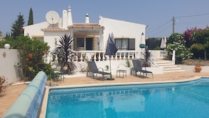 Un área junto a la piscina con sillones de descanso y una piscina.