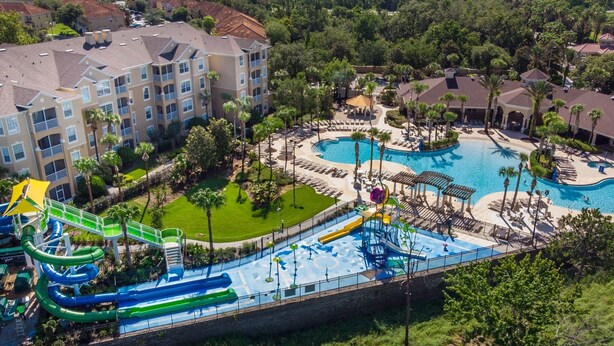 Ett semesterkomplex med flera pooler, en vattenpark och en stor byggnad med balkonger.