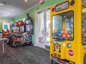 A room with arcade games, a yellow bumper car, and a 'Climbhouse Rules' sign.