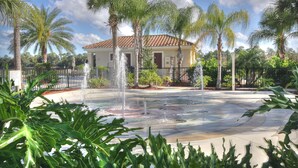 A house with a tiled roof, surrounded by palm trees and a fountain. - Disney Trail-Much loved 2 bedroom Oakwater condo, just 1.5 miles from Disney! (Kissimmee)
