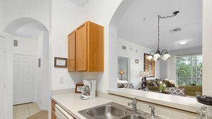 Una cucina moderna con due lavelli in acciaio inossidabile, mobili in legno, una macchina da caffè e un grande specchio che riflette l'area soggiorno.