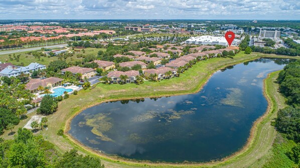 An aerial view of a residential area with houses, a large body of water, and a swimming pool.