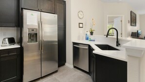 A modern kitchen with stainless steel appliances, a built-in water dispenser, and a sink with a black faucet. - Lakeside-Beautiful 3 bed Oakwater condo over the lake, just 1.5 miles from WDW! (Kissimmee)