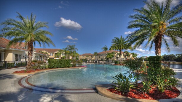 A swimming pool surrounded by palm trees and a residential area with houses. - Lakeside-Beautiful 3 bed Oakwater condo over the lake, just 1.5 miles from WDW! (Kissimmee)
