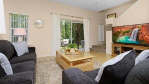 A living room with a sofa, a coffee table, and a television. - Disney Cove, Tranquil 3 bed Emerald Island townhome - Just 2.5 miles from WDW! (Four Corners)