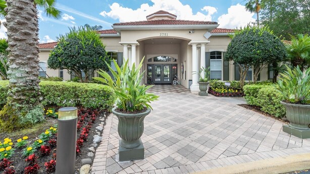 A hotel entrance with a tiled roof, a number '2751' above the doors, and a well-maintained garden with various plants and flowers. - Disney Cove, Tranquil 3 bed Emerald Island townhome - Just 2.5 miles from WDW! (Four Corners)