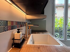 A modern kitchen with a large sink, a wooden countertop, and a tiled backsplash.