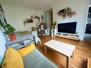 Un salon comprenant un canapé, une table basse, un téléviseur et une bibliothèque.